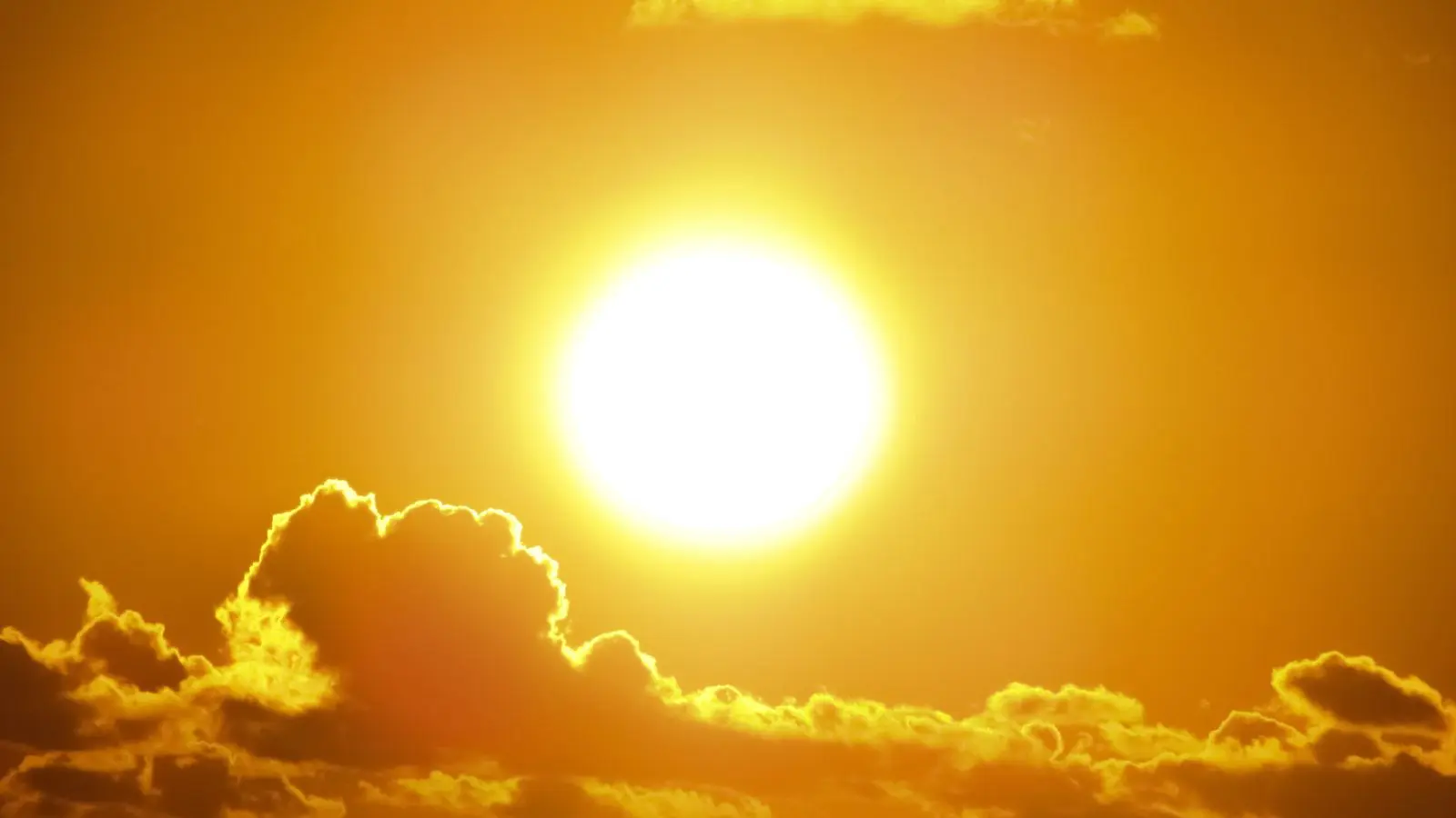 A blazing hot sun in a golden sky conveying an intense summer heatwave
